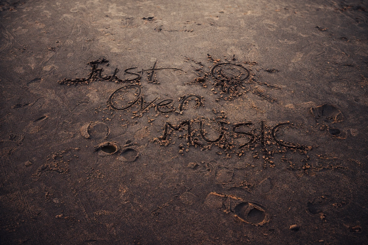 Words and a small sun drawn into sand among footprints.