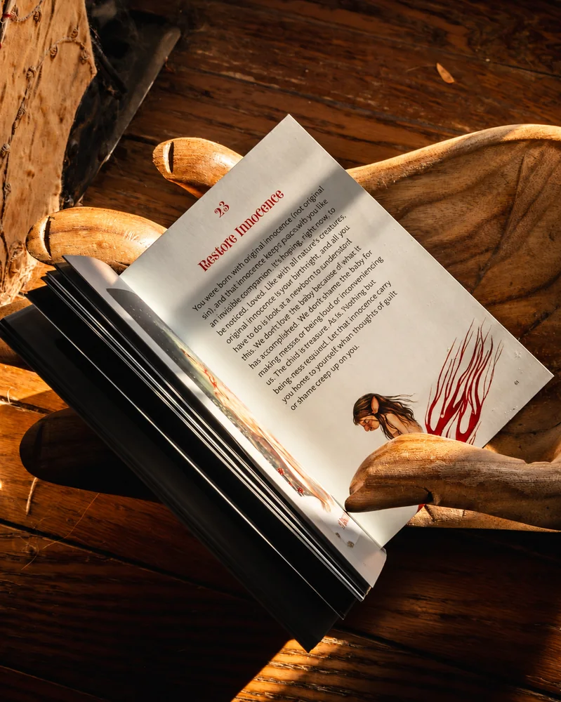 Ein offenes Buch liegt in geschnitzten Holzhänden; warmes Sonnenlicht fällt auf eine Seite mit der Überschrift „Unschuld wiederherstellen“.