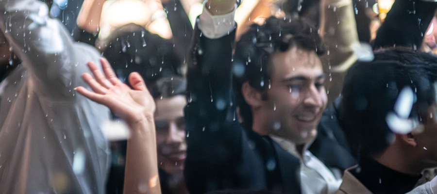 The Apex of the Evening A euphoric crowd smiling and dancing under falling confetti at a vibrant nightlife event.