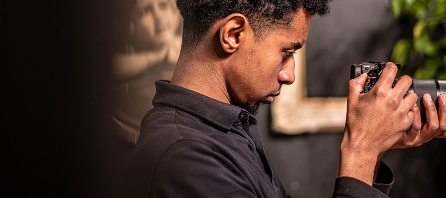 The Cinematic Eye Profile of a creator reviewing a shot on a mirrorless camera screen in a moody, dimly lit room.