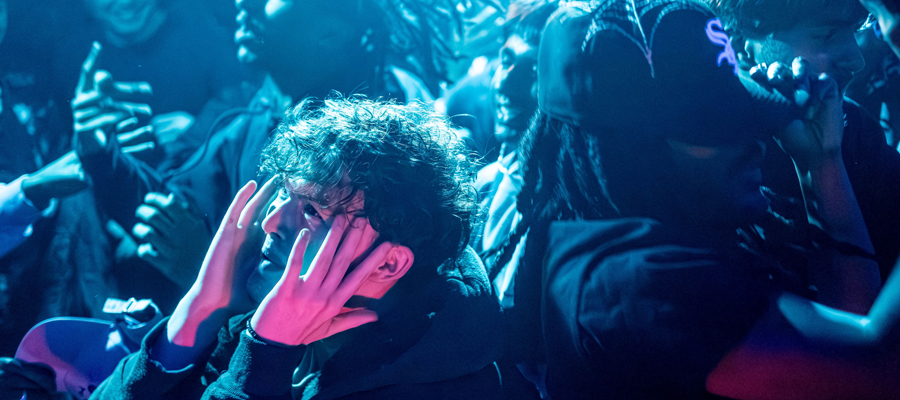 The Pulse of the Crowd A concert-goer dramatically holding their face in the middle of a vibrant, blue-lit crowd.
